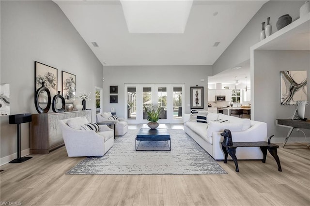 living room featuring high vaulted ceiling, light wood-type flooring, and french doors