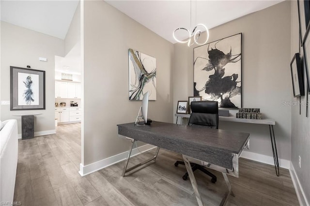 home office featuring hardwood / wood-style flooring, lofted ceiling, and a chandelier