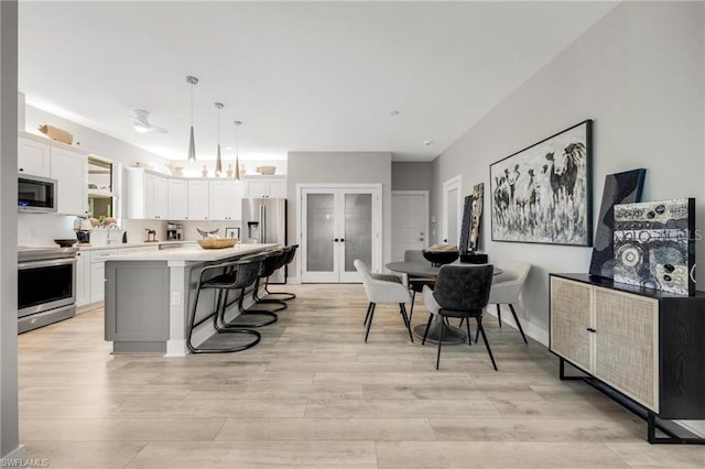 kitchen with a breakfast bar, white cabinetry, hanging light fixtures, appliances with stainless steel finishes, and a kitchen island