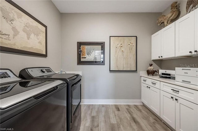 laundry room featuring light hardwood / wood-style floors, cabinets, and washing machine and clothes dryer