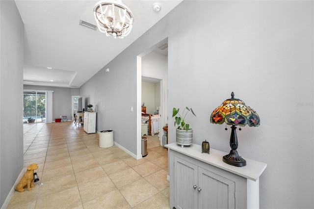 corridor featuring an inviting chandelier and light tile patterned floors