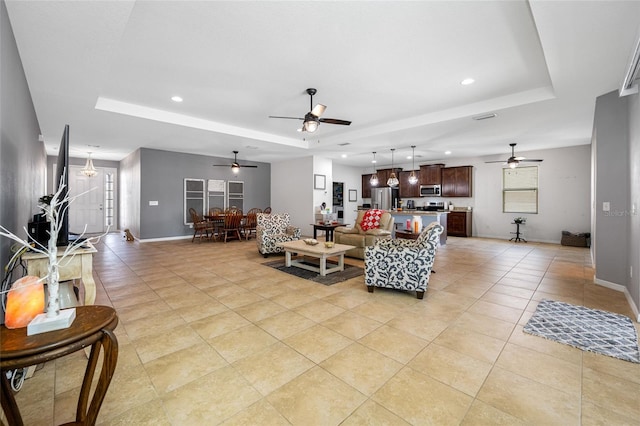 tiled living room featuring ceiling fan and a raised ceiling