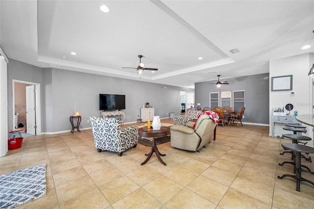 tiled living room featuring a tray ceiling and ceiling fan