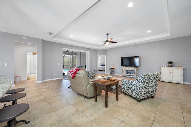 tiled living room with a raised ceiling and ceiling fan