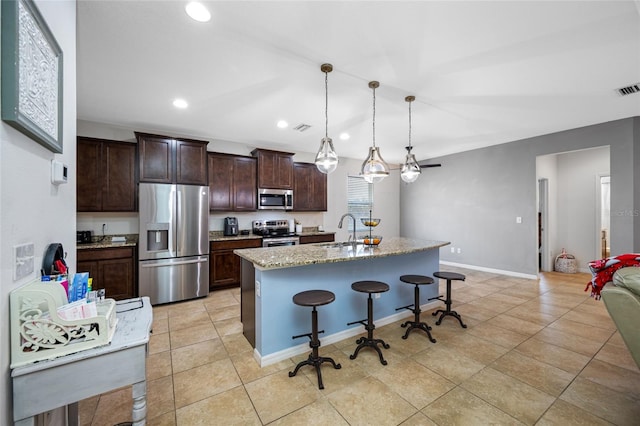 kitchen featuring sink, hanging light fixtures, a kitchen breakfast bar, stainless steel appliances, and a center island with sink