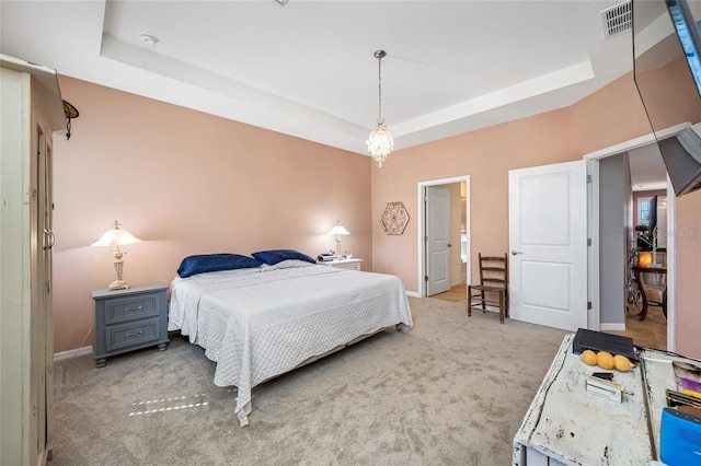 bedroom with light carpet and a tray ceiling