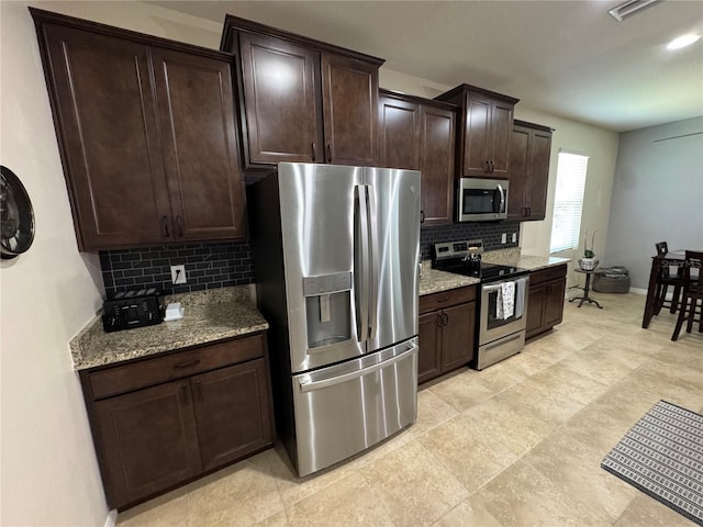 5821 Hevena Ct, Palmetto, FL 34221 - kitchen with stainless steel appliances, backsplash, light stone countertops, and dark brown cabinets