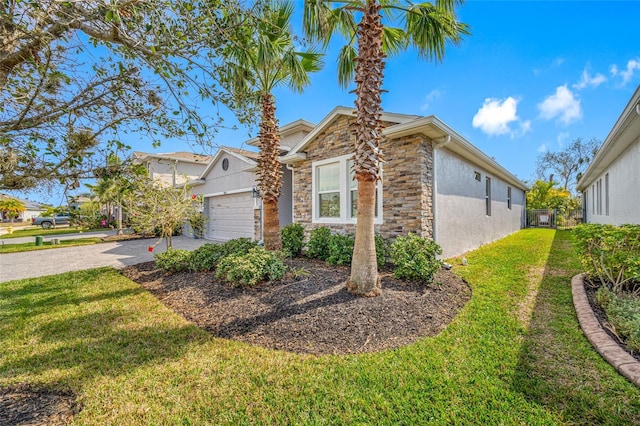 5821 Hevena Ct, Palmetto, FL 34221 - view of home's exterior featuring stone siding, an attached garage, driveway, a lawn, and stucco siding