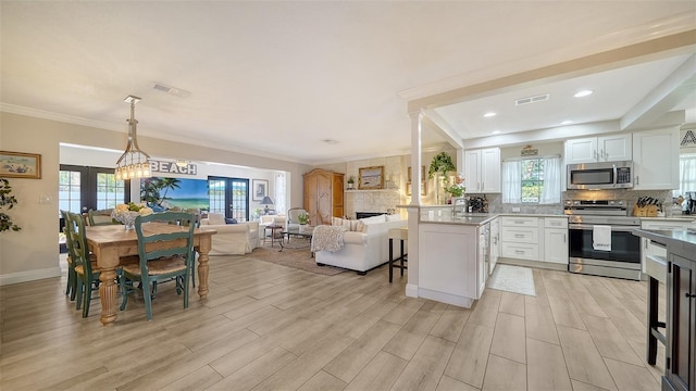 kitchen with french doors, appliances with stainless steel finishes, hanging light fixtures, and white cabinets