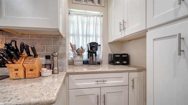 kitchen with white cabinetry, light stone counters, and tasteful backsplash