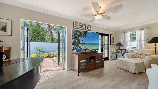 living area with ceiling fan, ornamental molding, and light wood-type flooring