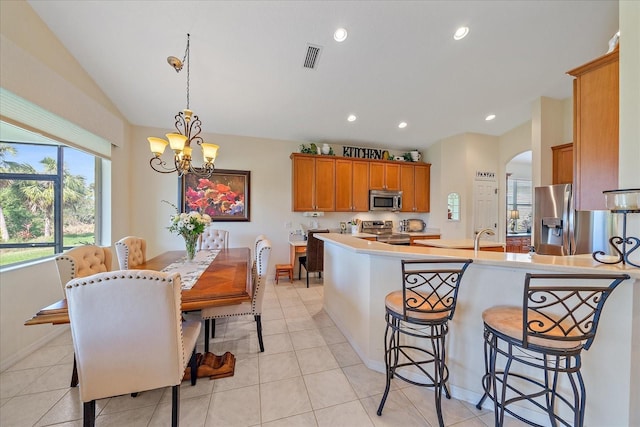 kitchen featuring sink, stainless steel appliances, a kitchen breakfast bar, light tile patterned flooring, and decorative light fixtures