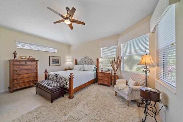 tiled bedroom with ceiling fan, vaulted ceiling, and a textured ceiling