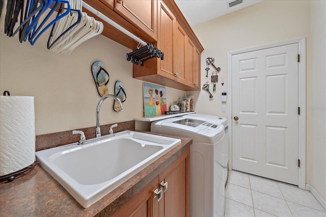 washroom featuring sink, light tile patterned floors, washer and clothes dryer, and cabinets