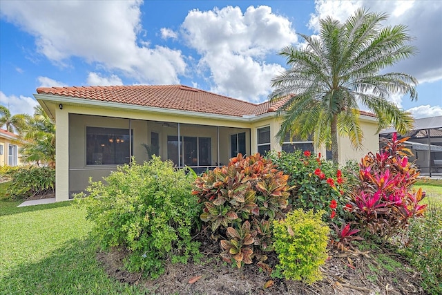 back of property featuring a yard and glass enclosure