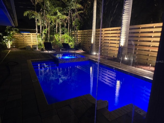 pool at twilight with an in ground hot tub