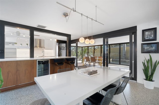 kitchen with sink, a breakfast bar area, wine cooler, hanging light fixtures, and a spacious island