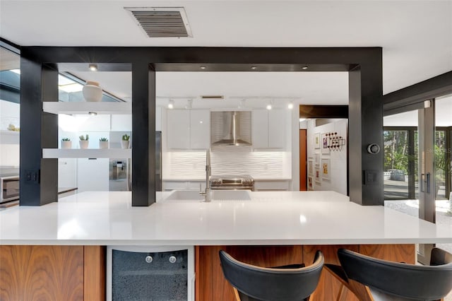 kitchen featuring white cabinetry, wall chimney exhaust hood, refrigerator, and sink