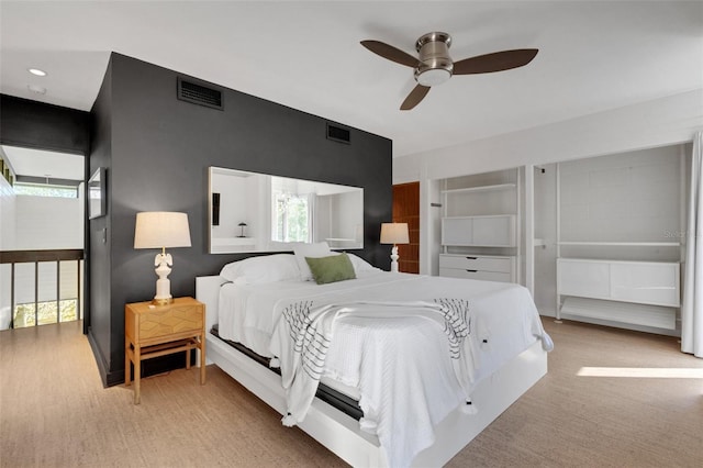 bedroom featuring ceiling fan, light colored carpet, and multiple windows