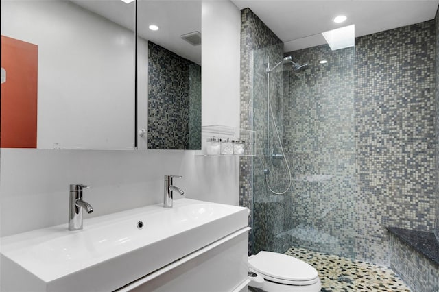 bathroom with tiled shower, vanity, and toilet