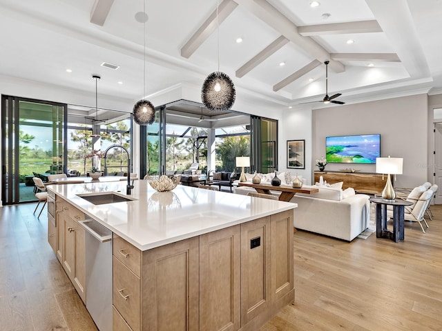 kitchen featuring dishwasher, open floor plan, light countertops, pendant lighting, and a sink