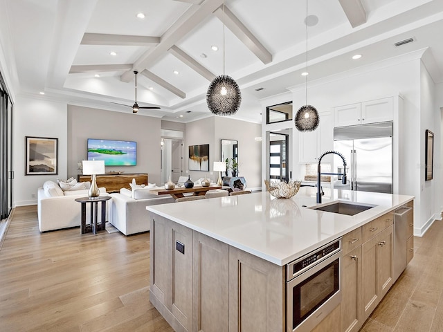 kitchen with light countertops, a sink, decorative light fixtures, and light brown cabinetry