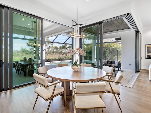 dining area featuring a sunroom, plenty of natural light, crown molding, and wood finished floors