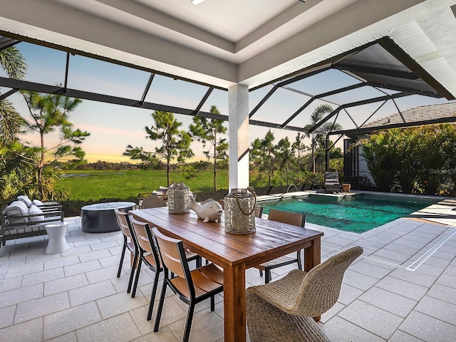 pool at dusk with outdoor dining area, an outdoor living space with a fire pit, a patio, a lanai, and an outdoor pool