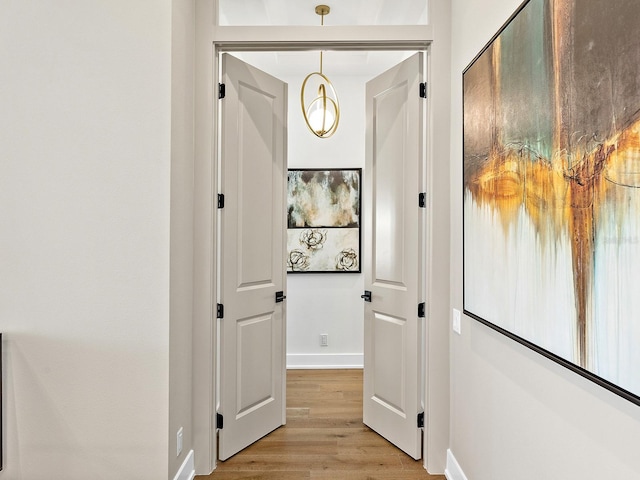 corridor with baseboards and light wood-style floors