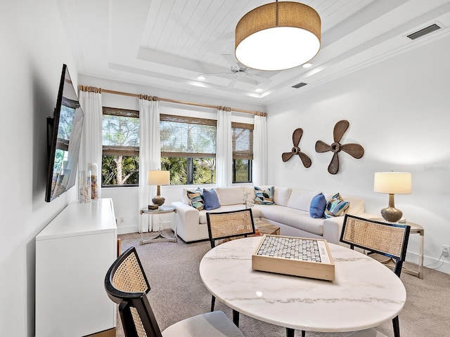 carpeted living area featuring a ceiling fan, a tray ceiling, visible vents, and baseboards