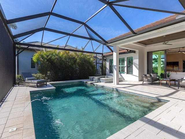 view of swimming pool with glass enclosure, outdoor lounge area, a pool with connected hot tub, a ceiling fan, and a patio area