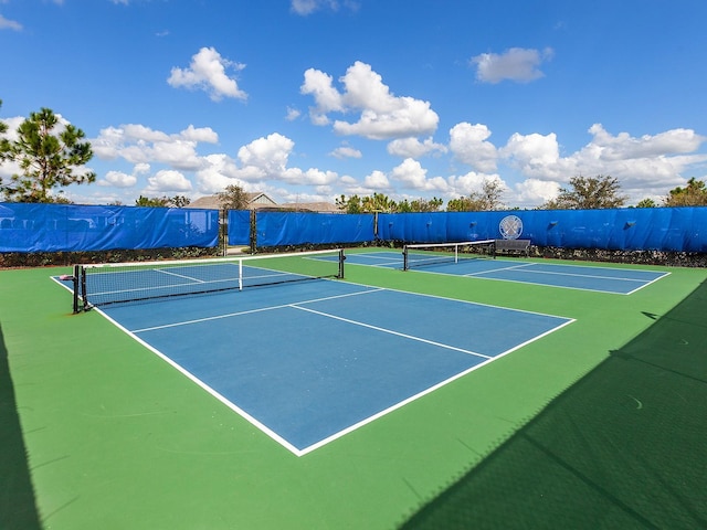 view of tennis court with community basketball court and fence