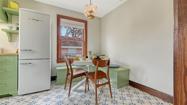 dining area featuring a chandelier, baseboards, and light floors