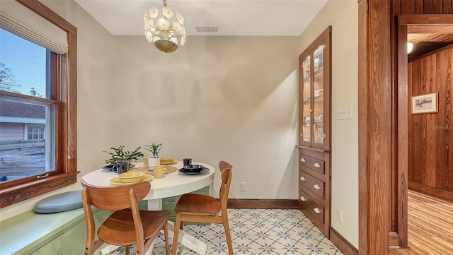 dining space featuring an inviting chandelier, baseboards, visible vents, and light floors