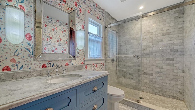 full bath featuring toilet, wallpapered walls, vanity, and a stall shower