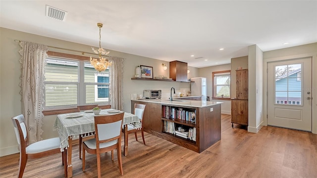 dining area featuring light wood finished floors, baseboards, and visible vents