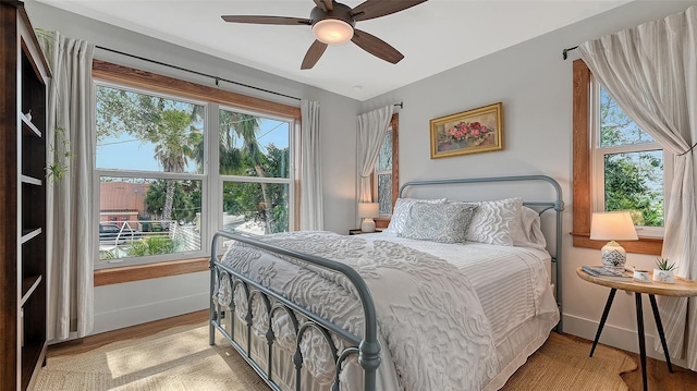 bedroom with a ceiling fan, baseboards, and light wood finished floors