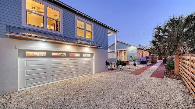 view of front of property featuring metal roof, fence, gravel driveway, and stucco siding