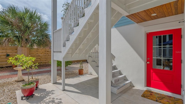 entrance to property featuring a patio area, fence, and stucco siding