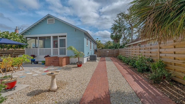 view of property exterior with a patio, central AC unit, a fenced backyard, and a sunroom