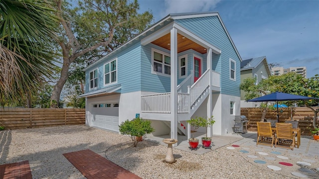 view of front of home featuring stairs, a patio, an attached garage, and fence