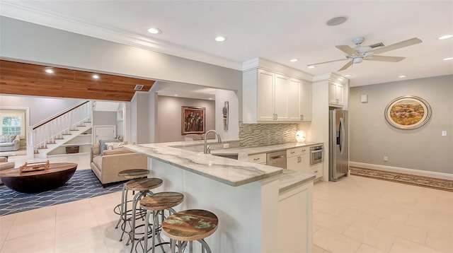 kitchen featuring white cabinetry, a kitchen breakfast bar, light stone counters, kitchen peninsula, and stainless steel appliances