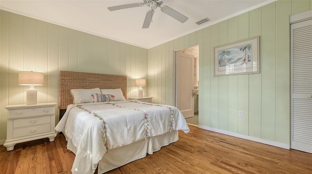 bedroom featuring hardwood / wood-style flooring, ornamental molding, ceiling fan, and a closet