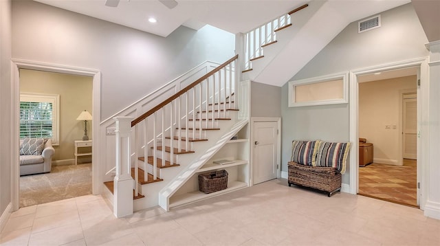 stairs with a high ceiling, built in features, tile patterned floors, and ceiling fan