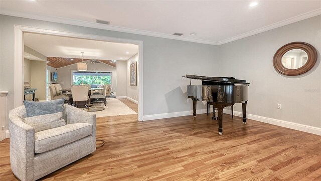 sitting room with ornamental molding, light hardwood / wood-style floors, and vaulted ceiling