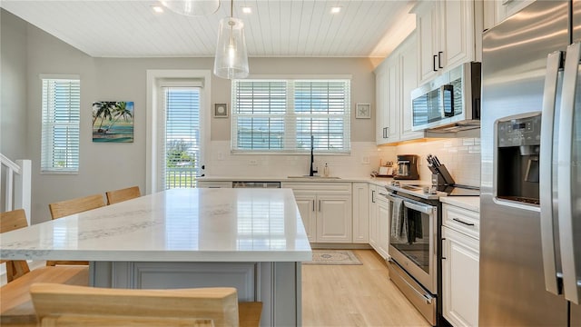 kitchen with sink, a breakfast bar, hanging light fixtures, stainless steel appliances, and a kitchen island