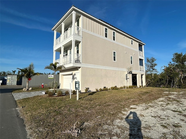 view of side of property featuring a balcony, a garage, and a lawn