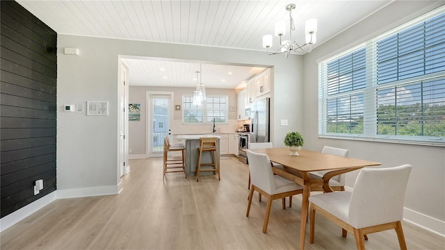 dining space featuring light wood finished floors, wood ceiling, a chandelier, and a healthy amount of sunlight