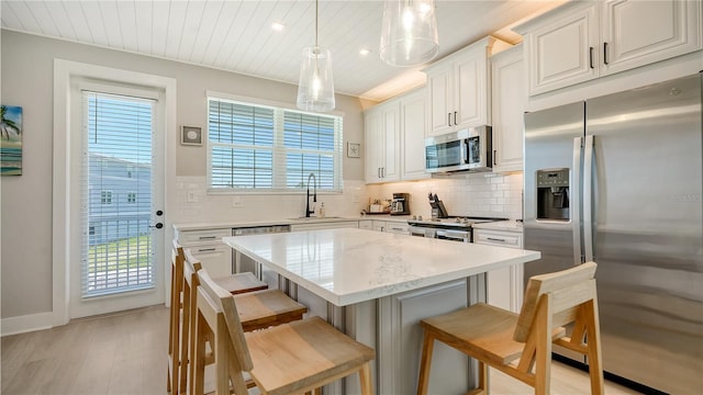 kitchen with backsplash, plenty of natural light, stainless steel appliances, and a sink