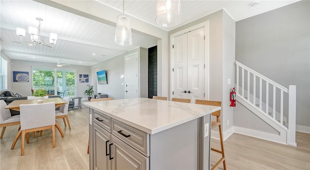 kitchen with light wood finished floors, an inviting chandelier, open floor plan, a center island, and hanging light fixtures